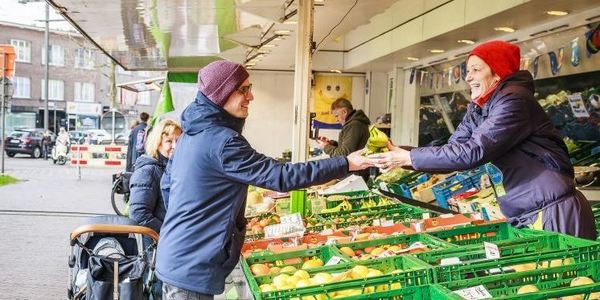 Een klant koopt fruit op de dinsdagmarkt op de Bist.