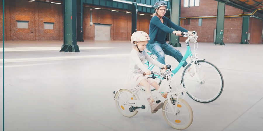 Meisje op haar fiets begeleid door haar mama op de fiets