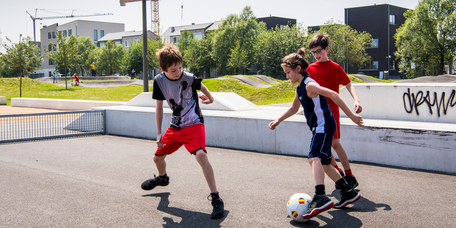 Drie kinderen spelen voetbal in het Regattapark Drie kinderen spelen voetbal in het Regattapark