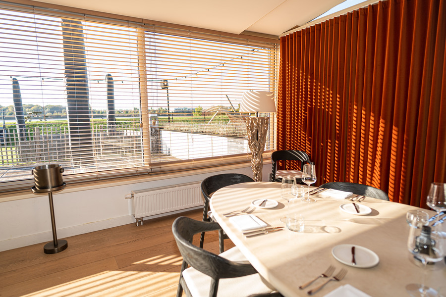 Tafel aan het raam naast een oranje gordijn