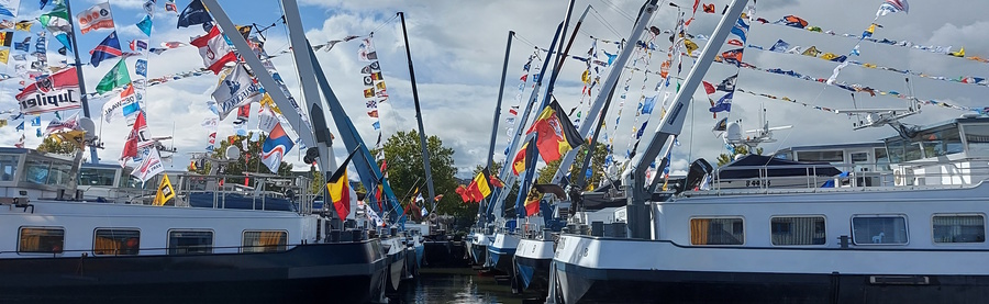 8 motorvrachtschepen met achtersteven naar elkaar gemeerd en veel kleurrijke vlaggen op de schepen 8 motorvrachtschepen met achtersteven naar elkaar gemeerd en veel kleurrijke vlaggen op de schepen