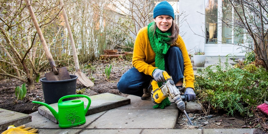 Vrouw haalt met breekhamer stenen uit de tuin. Vrouw haalt met breekhamer stenen uit de tuin.