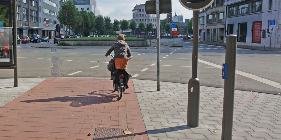 Fietser staat aan een verkeerslicht met drukknop Fietser staat aan een verkeerslicht met drukknop