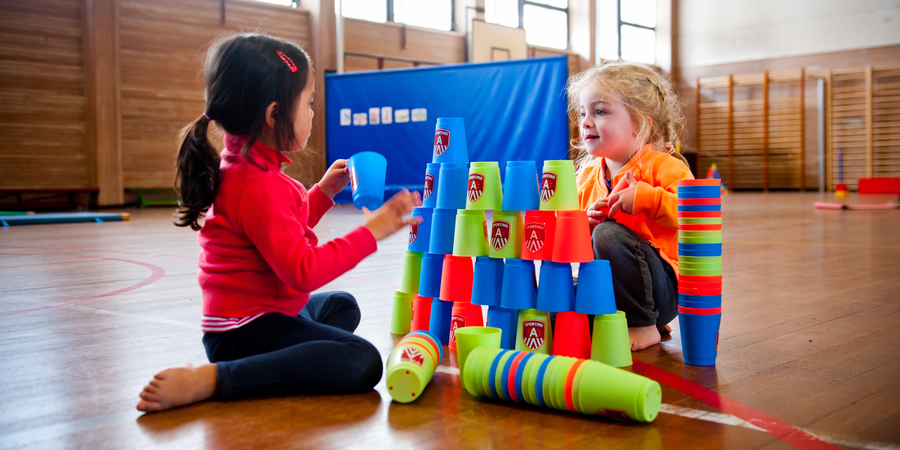 Twee meisjes bouwen een toren met stapelbekers Twee meisjes bouwen een toren met stapelbekers