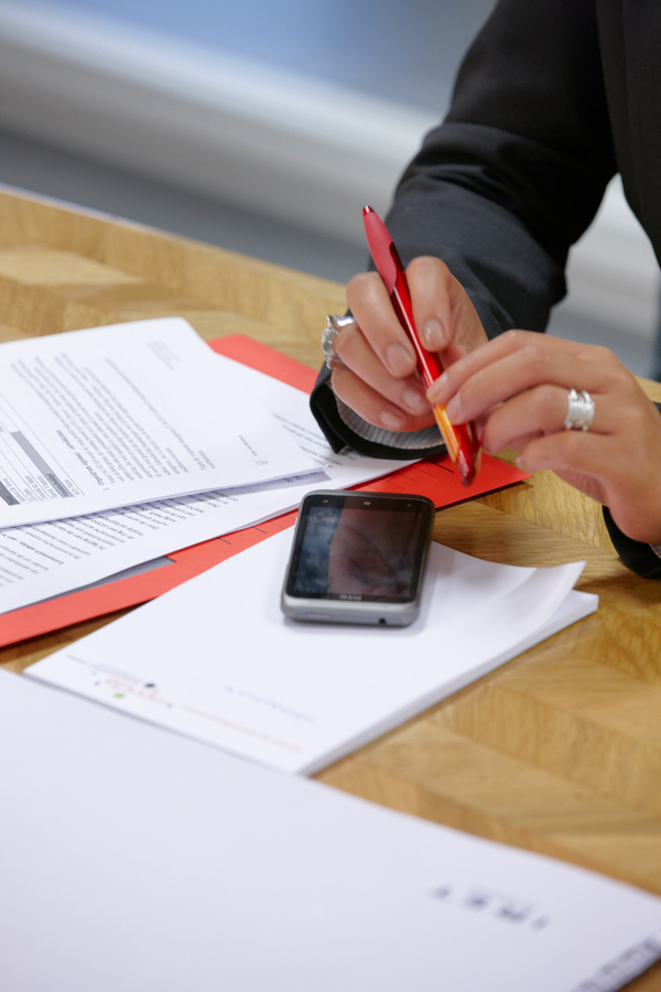 Persoon aan tafel met smartphone en documenten