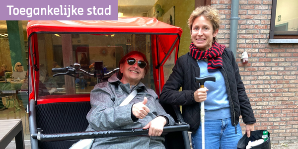 Iemand met visuele beperking zit een fietstaxi en begeleider staat ernaast