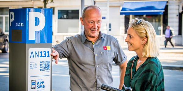 Parkeerwachters en vrouw staan naast een parkeerautomaat