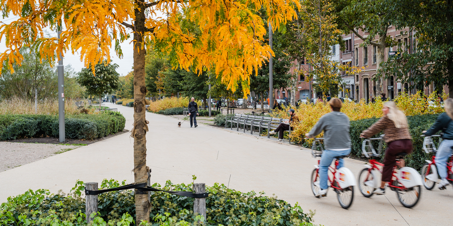 Beeld van het nieuwe Zuidpark waar drie mensen op de voorgrond naast elkaar fietsen op een Velo Beeld van het nieuwe Zuidpark waar drie mensen op de voorgrond naast elkaar fietsen op een Velo