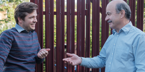 Twee mannen praten als buren met elkaar over dingen uit het dagelijks leven.