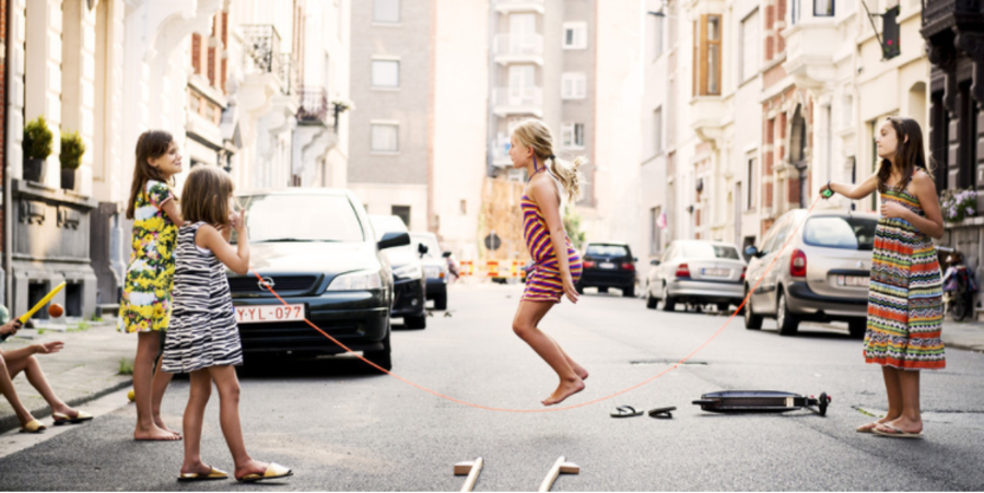 Vier kinderen spelen samen met een springtouw in een afgesloten speelstraat