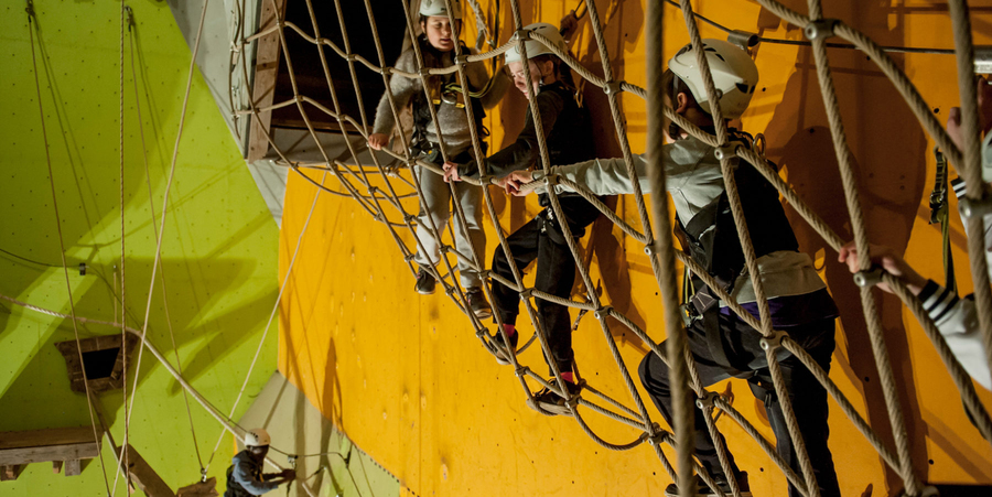Drie kinderen klimmen in een touwparcours. Ze dragen helmen. Drie kinderen klimmen in een touwparcours. Ze dragen helmen.