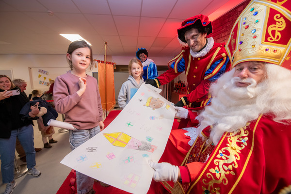 Kindjes poseren met een tekening bij Sinterklaas