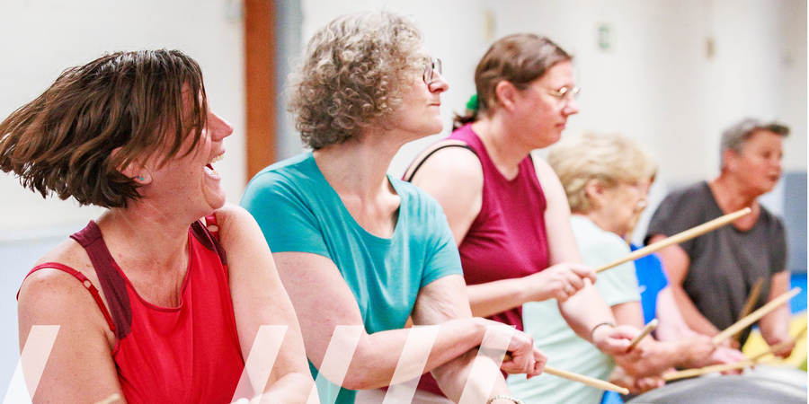 Vrouwen slaan met drumstokjes op een grote bal