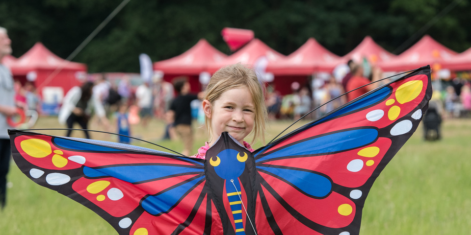 Meisje poseert met vlieger in de vorm van een vlinder