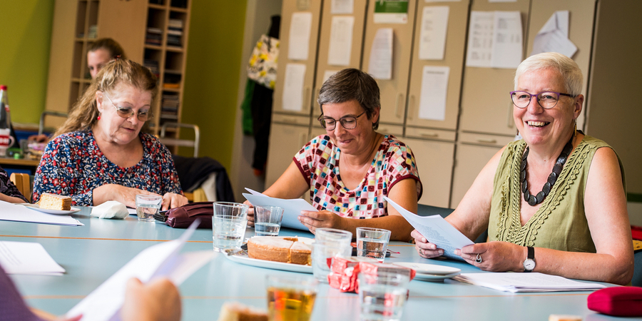 Dames lezen samen aan tafel Dames lezen samen aan tafel