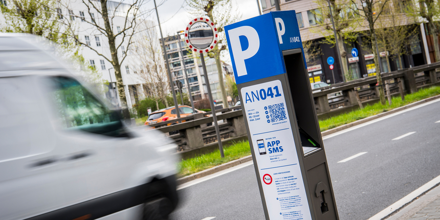 Bestelwagen rijdt langs een parkeerautomaat