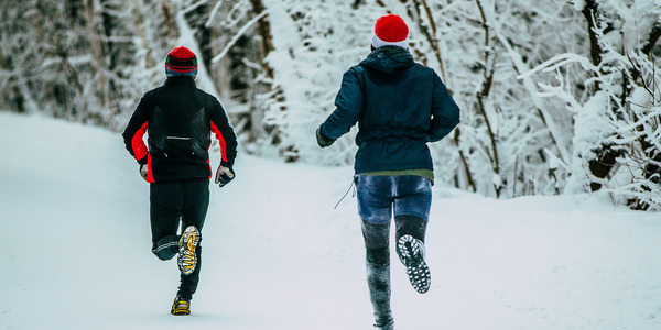 Lopers met kerstmuts in de sneeuw