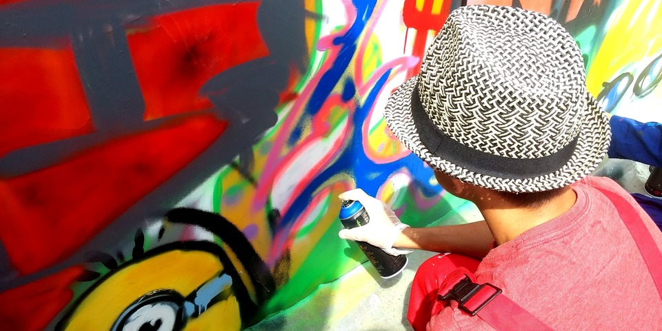 Een jongere aan de slag met graffiti-spuitbussen.