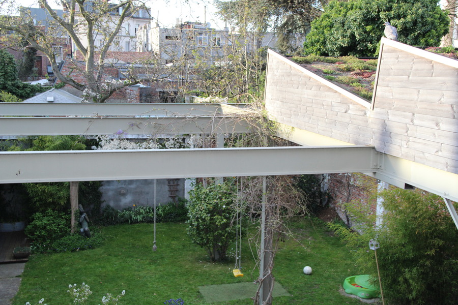 Klimplant slingert langs stalen balken boven een stadstuin