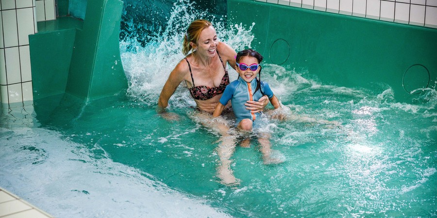 Vrouw met kind op de schoot komen beneden aan in de waterglijbaan