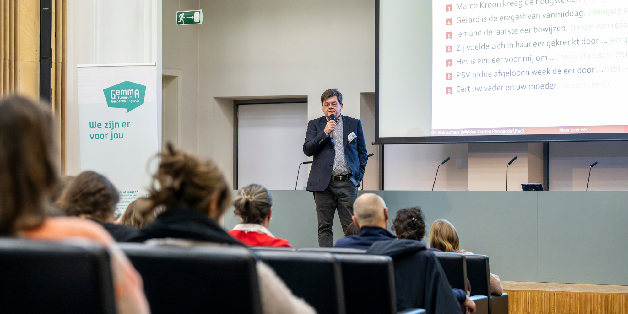 Rob Ermers staat met micro vooraan in auditorium Rob Ermers staat met micro vooraan in auditorium