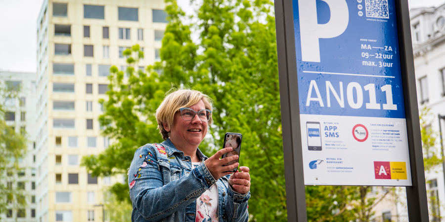 Vrouw staat naast een parkeerinformatiebord Vrouw staat naast een parkeerinformatiebord