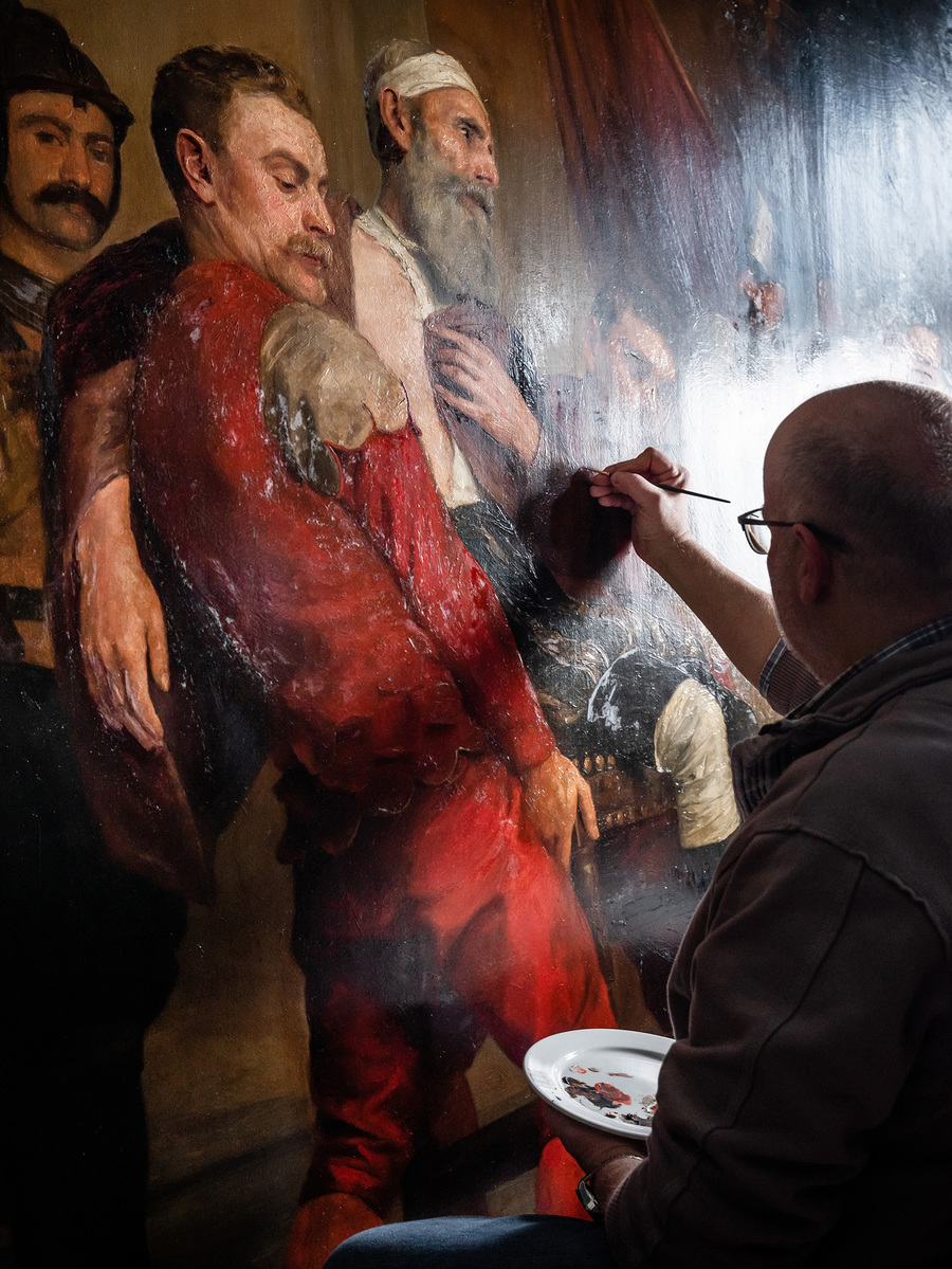 Restaurator Marc Leenaerts werkt het schilderij bij met een fijn penseel.