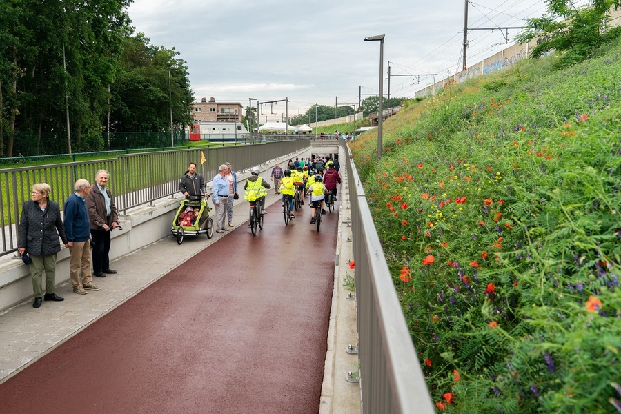 Schoolkinderen en omwonenden fietsen en wandelen op de helling naar de tunnel komende van Bist.