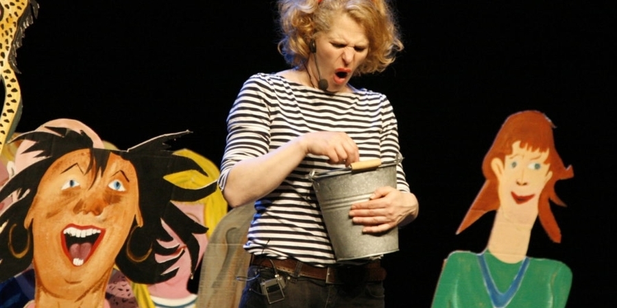 Een vrouw staat op een podium met een emmer. Naast haar kartonnen bordfiguren. Een vrouw staat op een podium met een emmer. Naast haar kartonnen bordfiguren.