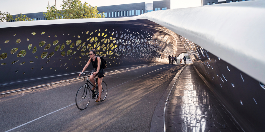 Een vrouw fietst over de Parkbrug in Antwerpen. Op de achtergrond wandelen enkele voetgangers. Een vrouw fietst over de Parkbrug in Antwerpen. Op de achtergrond wandelen enkele voetgangers.