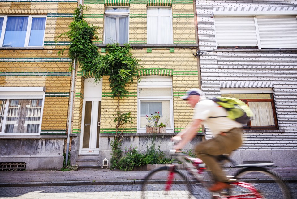 Fietser rijdt voorbij een rijhuis met een groenslinger aan bevestigd.