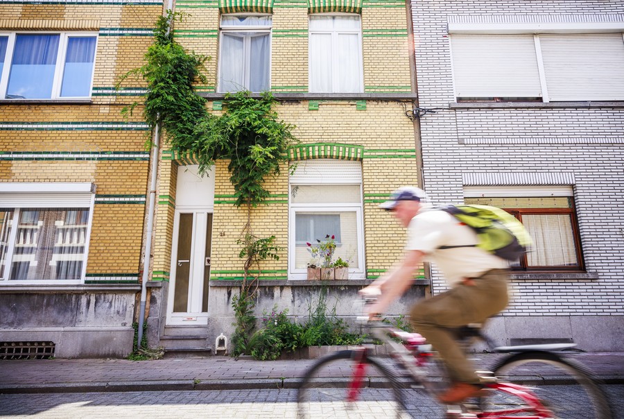 Fietser rijdt voorbij een rijhuis met een groenslinger aan bevestigd. Fietser rijdt voorbij een rijhuis met een groenslinger aan bevestigd.