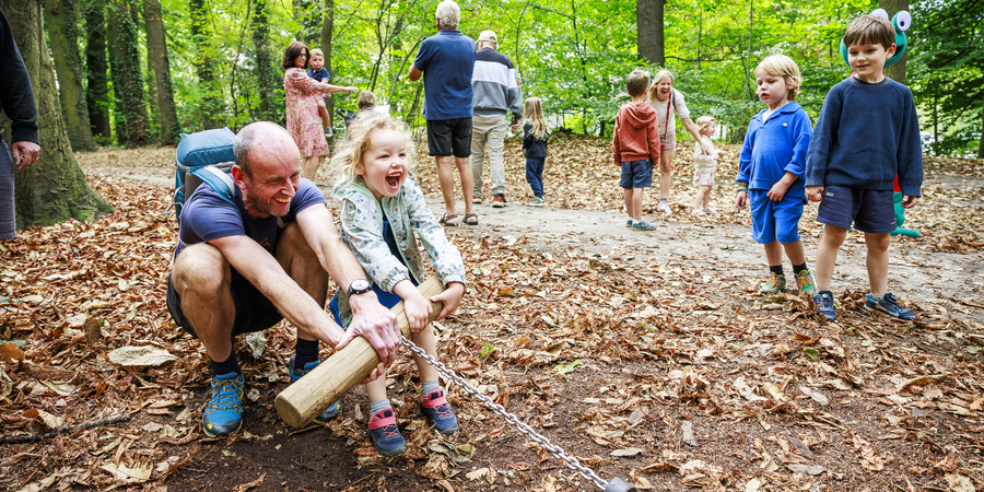 man en kind spelen in bos aan bewegingstoestel