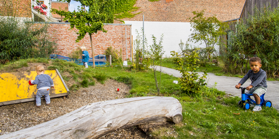 De groene en avontuurlijke buitenruimte van een kinderdagverblijf waarop peuters spelen De groene en avontuurlijke buitenruimte van een kinderdagverblijf waarop peuters spelen