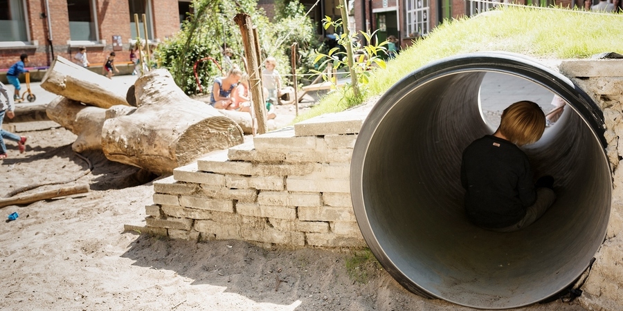 Een jongen zit rustig in de tunnel van een speelheuvel Een jongen zit rustig in de tunnel van een speelheuvel