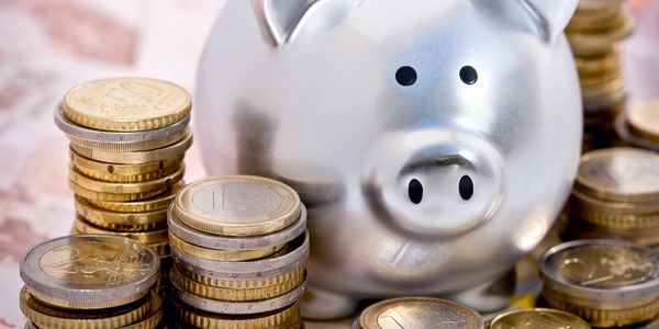 Een zilveren geldvarken omringd door stapels euromunten.