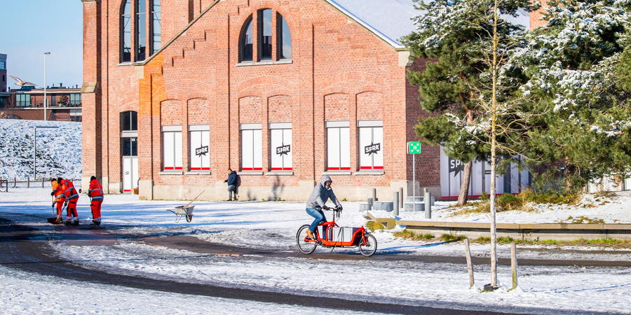 Sneeuw in Park Spoor Noord met een fietser en stadsmedewerkers die sneeuw en ijs ruimen