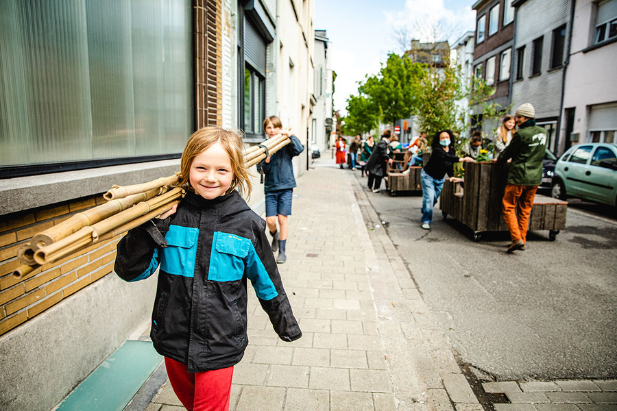 Foto van kinderen die vlaggenmasten van een parklet dragen