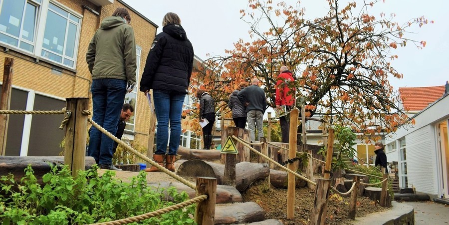 Groene speelplaats met waarschuwingsbordje voor uitglijdingsgevaar bj de boomstammen Groene speelplaats met waarschuwingsbordje voor uitglijdingsgevaar bj de boomstammen