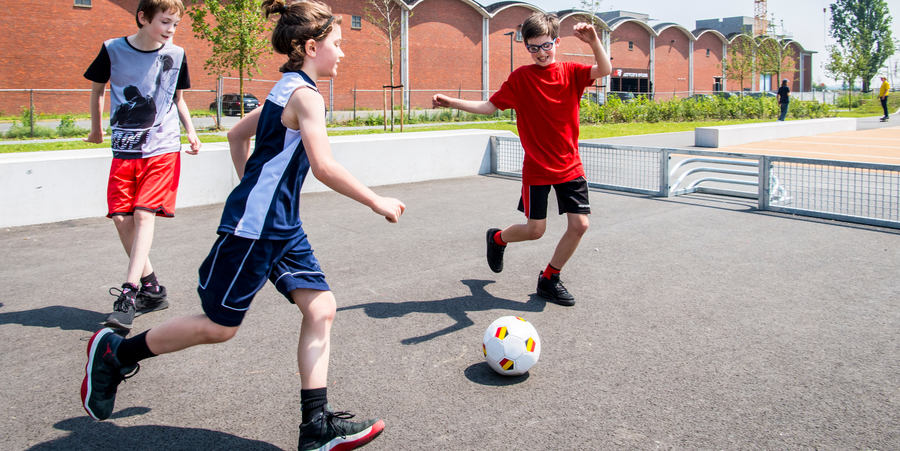 Drie kinderen zijn aan het voetballen op een pannavoetbalveld. Drie kinderen zijn aan het voetballen op een pannavoetbalveld.
