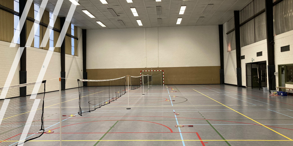 Overzichtsfoto van een lege sporthal met badmintonnetten opgesteld