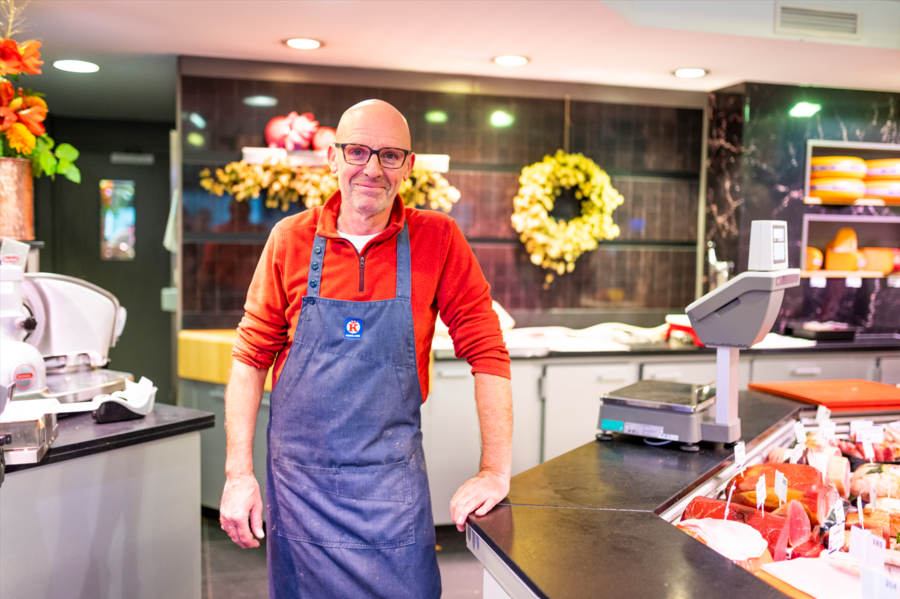 Portretfoto van slager naast vleestoog
