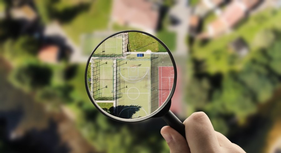 Een vergrootglas waar je verschillende soorten sportterreinen in ziet. De omgeving is wazig.