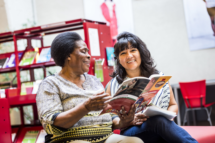 Rosario en een andere vrouw kijken in een kookboek. Rosario en een andere vrouw kijken in een kookboek.