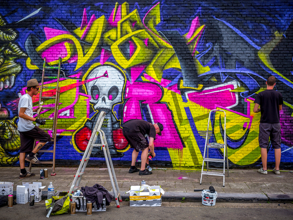 Streetart-artiesten zijn in de weer met spuitbussen op een muur. Streetart-artiesten zijn in de weer met spuitbussen op een muur.