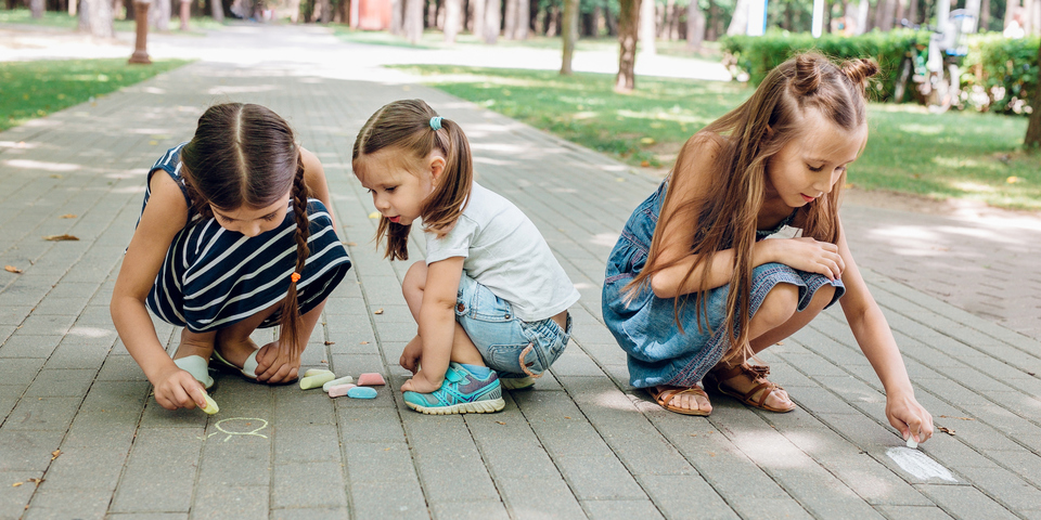 3 meisjes tekenen met krijt op de straat