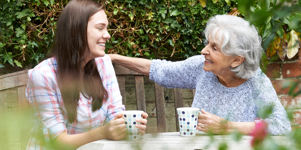 Een jonge vrouw en oude dame drinken samen koffie. Het is een klein gebaar, maar het maakt een groot verschil voor iemand die eenzaam is.