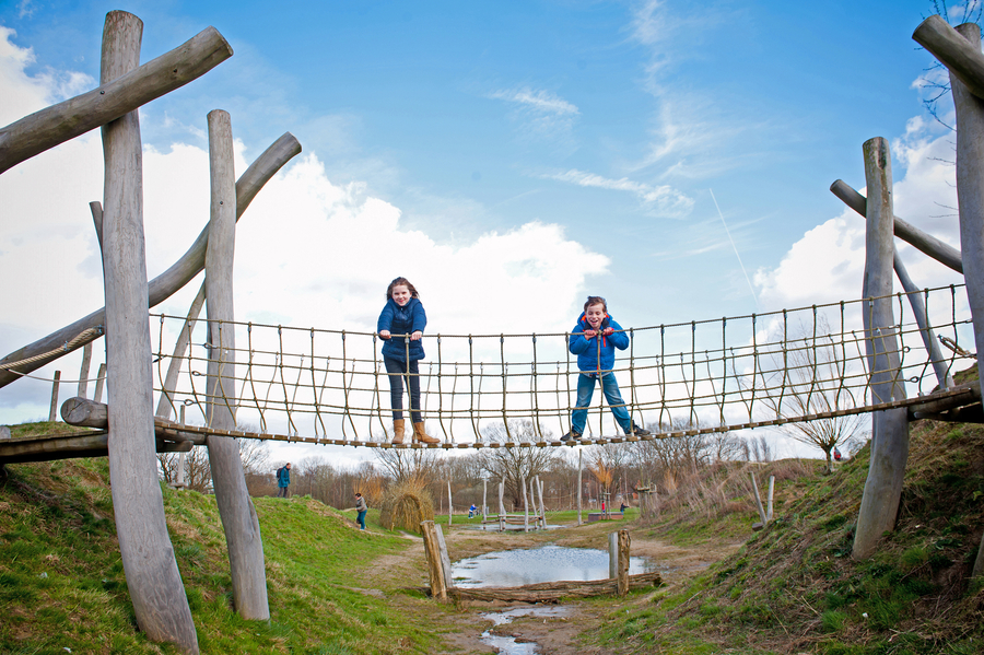 Een jongen en een meisje staan op een loopbrug over het speelterrein van het Park van Eden. Een jongen en een meisje staan op een loopbrug over het speelterrein van het Park van Eden.