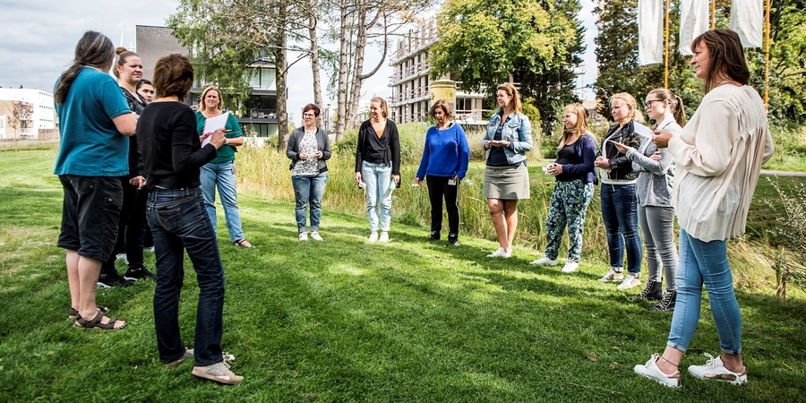 Een groep mensen staat in een kring om naar een opdracht te luisteren Een groep mensen staat in een kring om naar een opdracht te luisteren