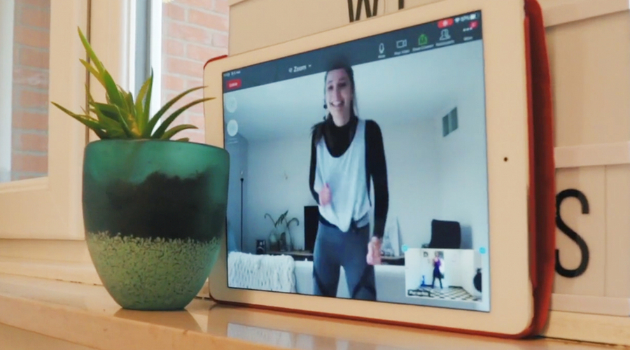 Een tablet op de vensterbank met op het scherm een vrouw die online sportles volgt Een tablet op de vensterbank met op het scherm een vrouw die online sportles volgt